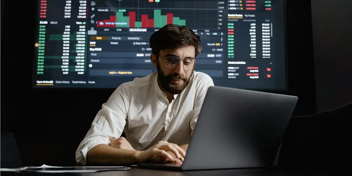 A man with his laptop and chart behind him
